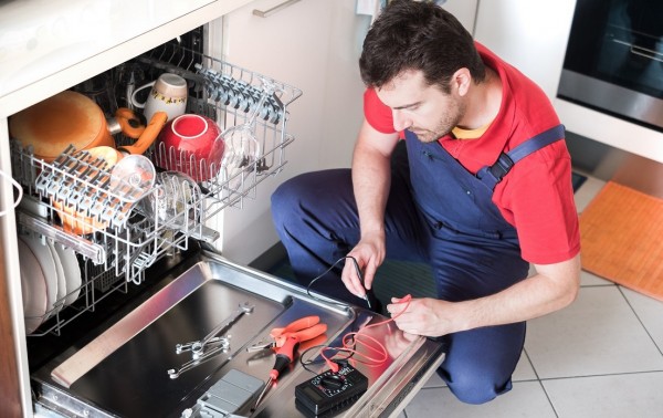 Worker repairing the dishwasher in the kitchen